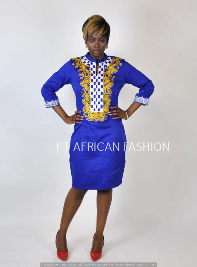Frontal of model wearing a blue pencil dress with gold African embroidery detail and checker print on the front.