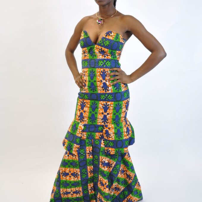 Side shot of model wearing a a strapless long peplum fit and flare occasion dress in all over multi-coloured African Ankara print.