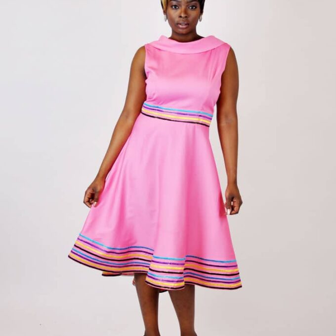 Frontal of model wearing a 1960s style pink skater dress. with v neck at the back for an elegant look.