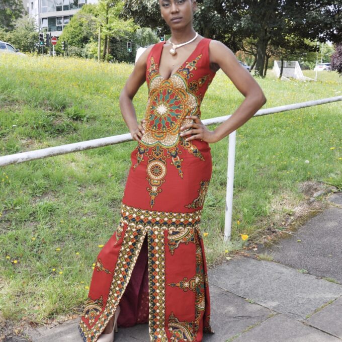 Full frontal of model wearing a red sleeveless fit and flare floor-length statement dress with African dashiki print. Also has slits to front and rear. Perfect for a special occasion!
