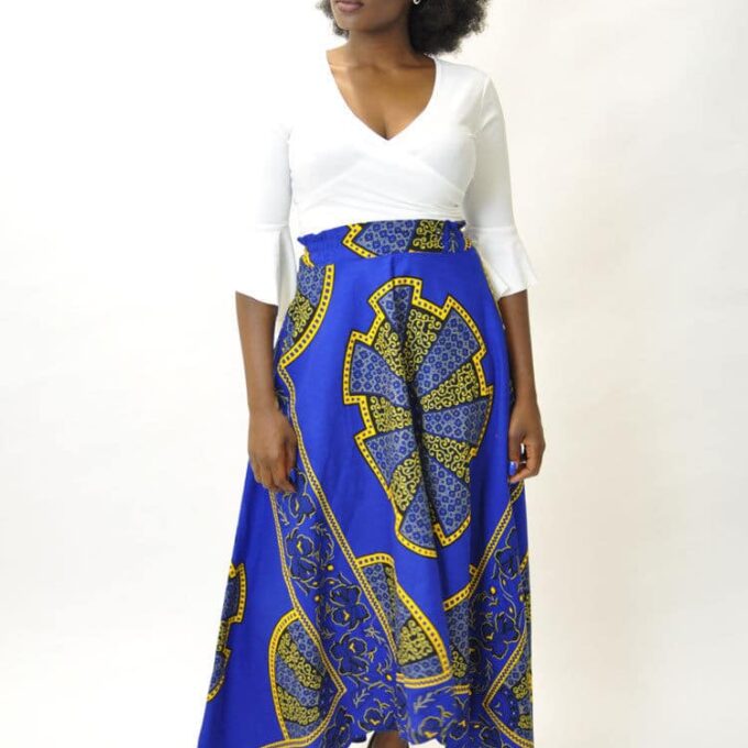 Frontal of model wearing a blue and gold African Ankara print maxi skirt with dip hem / high low design.