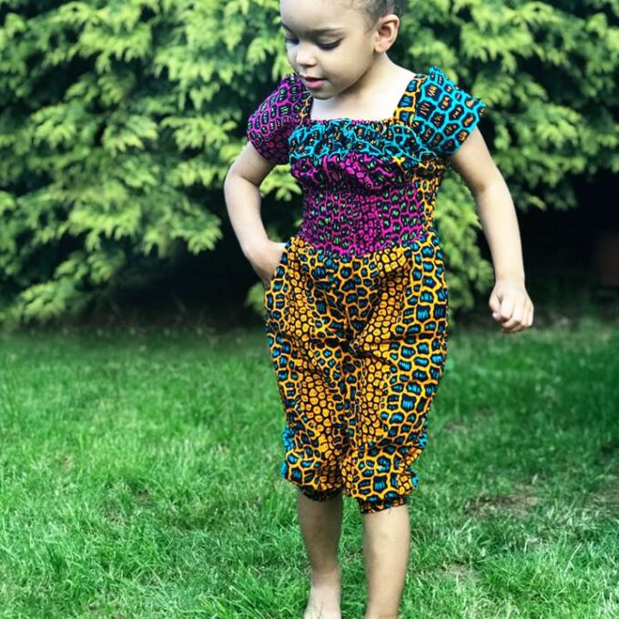 Frontal of model wearing a colourful African Ankara jumpsuit in all over animal print pattern.