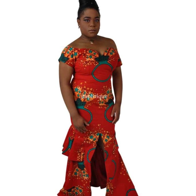Full frontal of model wearing a red off shoulder long fit and flare occasion dress with sweetheart neckline, front slit, peplum ruffles on the back in all over Ankara ring and star print.
