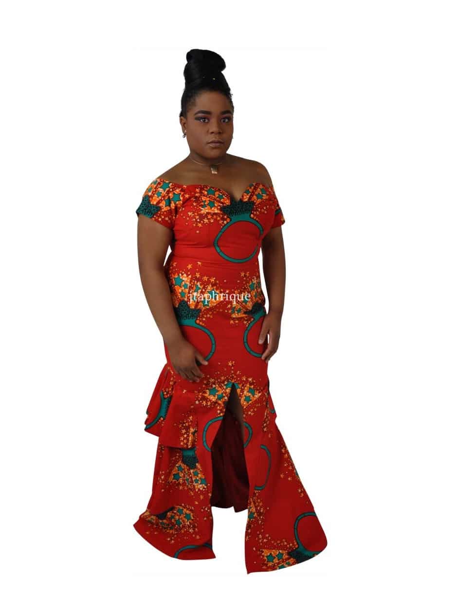Full frontal of model wearing a red off shoulder long fit and flare occasion dress with sweetheart neckline, front slit, peplum ruffles on the back in all over Ankara ring and star print.