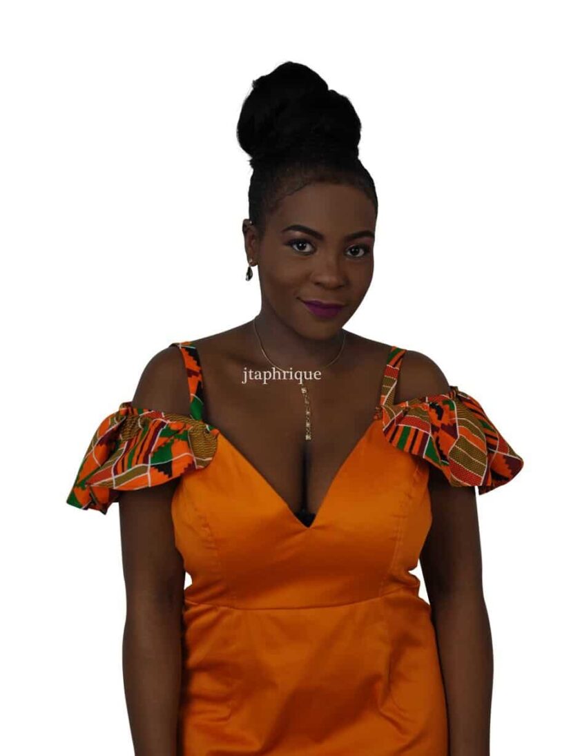 Close shot of model wearing a solid orange & African Kente print ruffle occasion dress with a cold shoulder neckline.