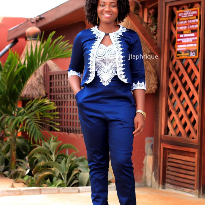Full frontal of model wearing a ladies navy jumpsuit with silver African embroidery on the front of jumpsuit, bolero cuffs and collar trim and edges..