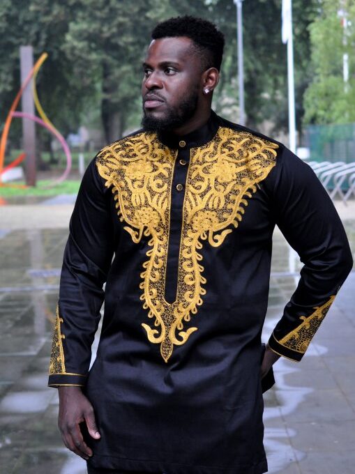 Close shot of model wearing our custom made black African suit with intricate gold embroidery which can be customised.