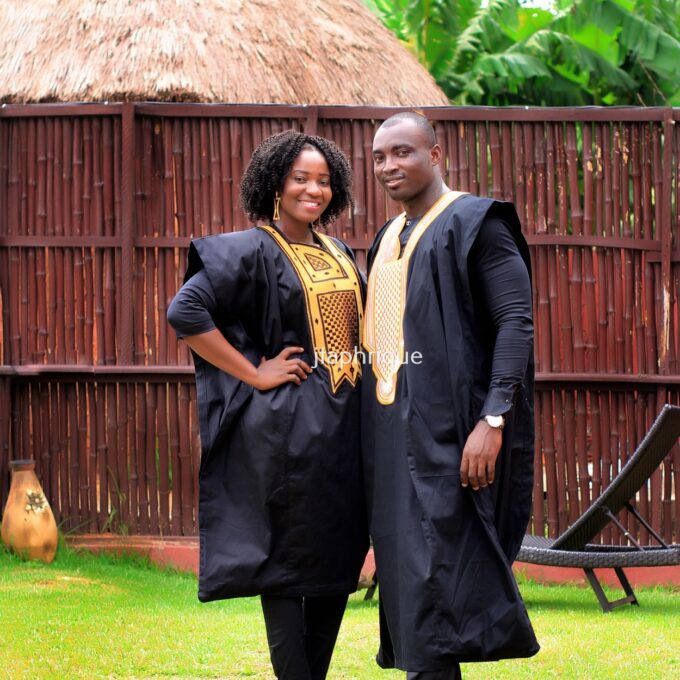 Frontal of male and female models wearing Mr & Mrs or his and hers matching traditional African suit outfits for couples, in black with gold embroidery. Perfect for a special occasion, wedding or Eid.