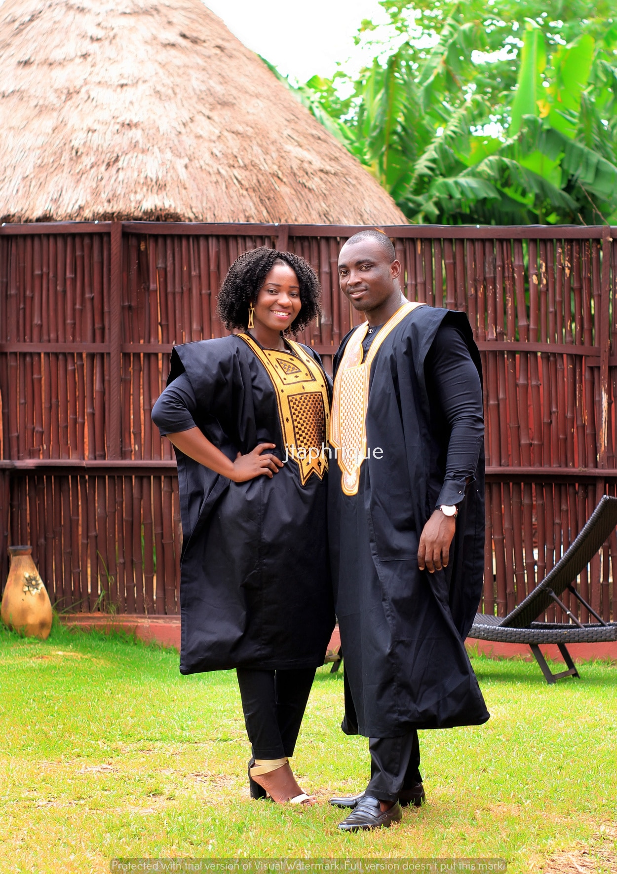 Frontal of male and female models wearing Mr & Mrs or his and hers matching traditional African suit outfits for couples, in black with gold embroidery. Perfect for a special occasion, wedding or Eid.