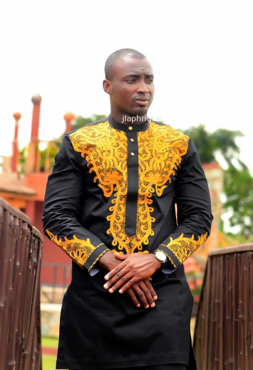Close front shot of model wearing a solid black suit with gold African embroidery.