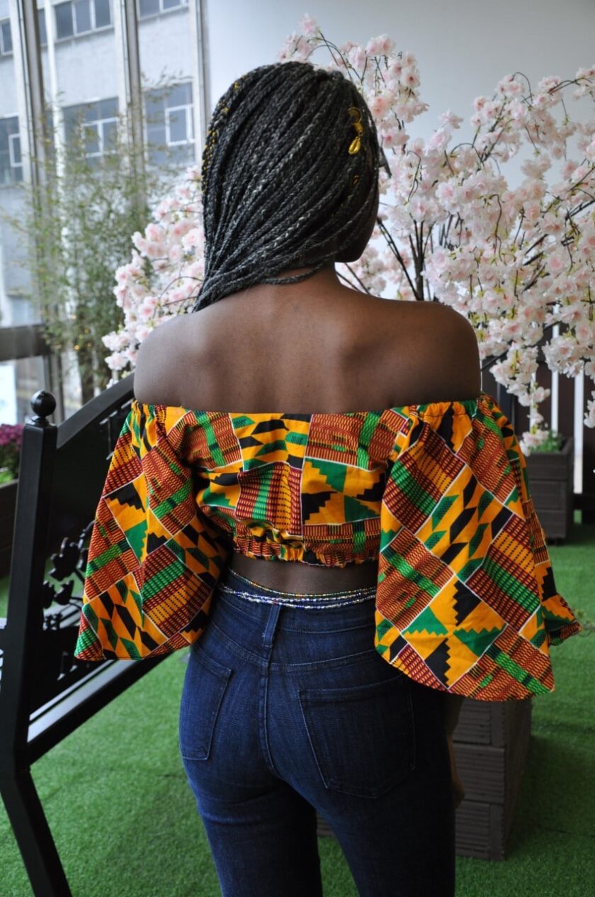 Back shot of another model wearing a colourful butterfly sleeve crop top in all over African print.