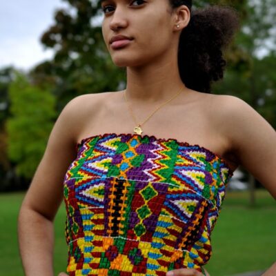 Close-up of model wearing a colourful tube top in all over African Kente print pattern.