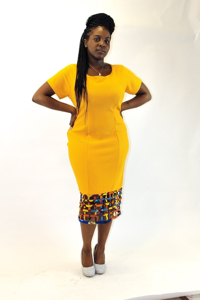 Frontal of model wearing a yellow bodycon dress with mesh hem detail in African print.