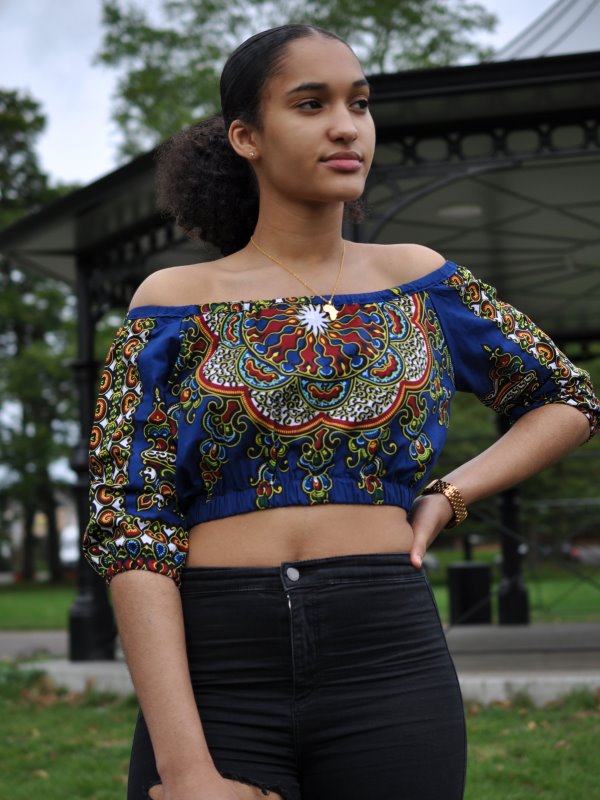 Frontal of model wearing a blue off shoulder boho crop top in all over African print pattern.