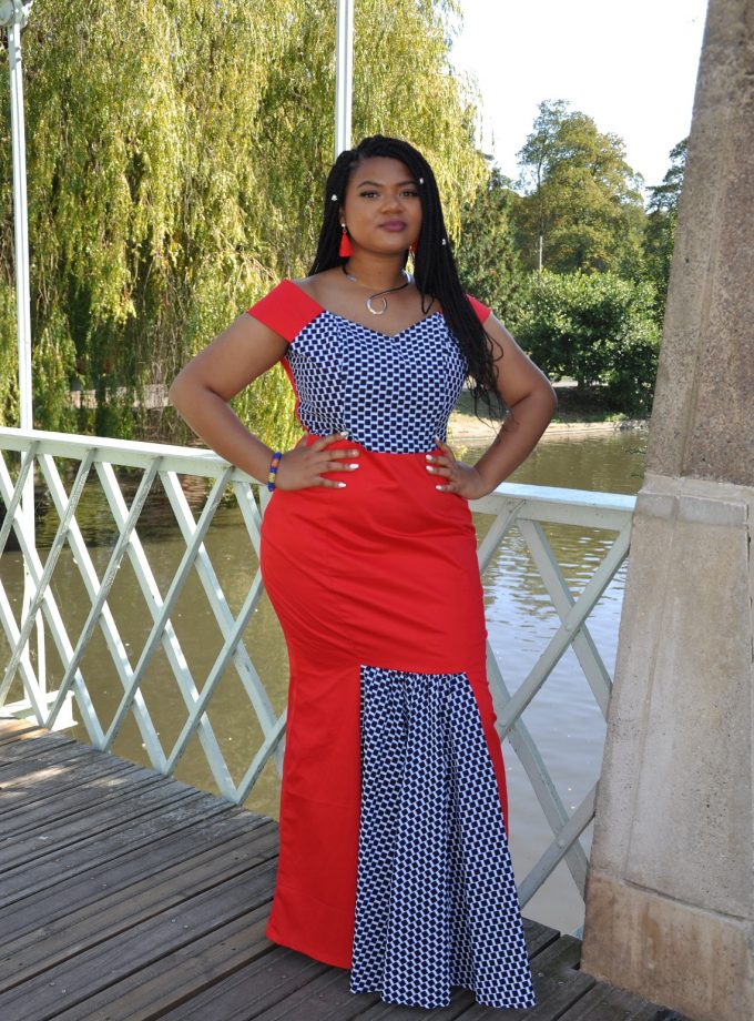 Frontal of model wearing a red and African Ankara print fusion occasion dress with fishtail.