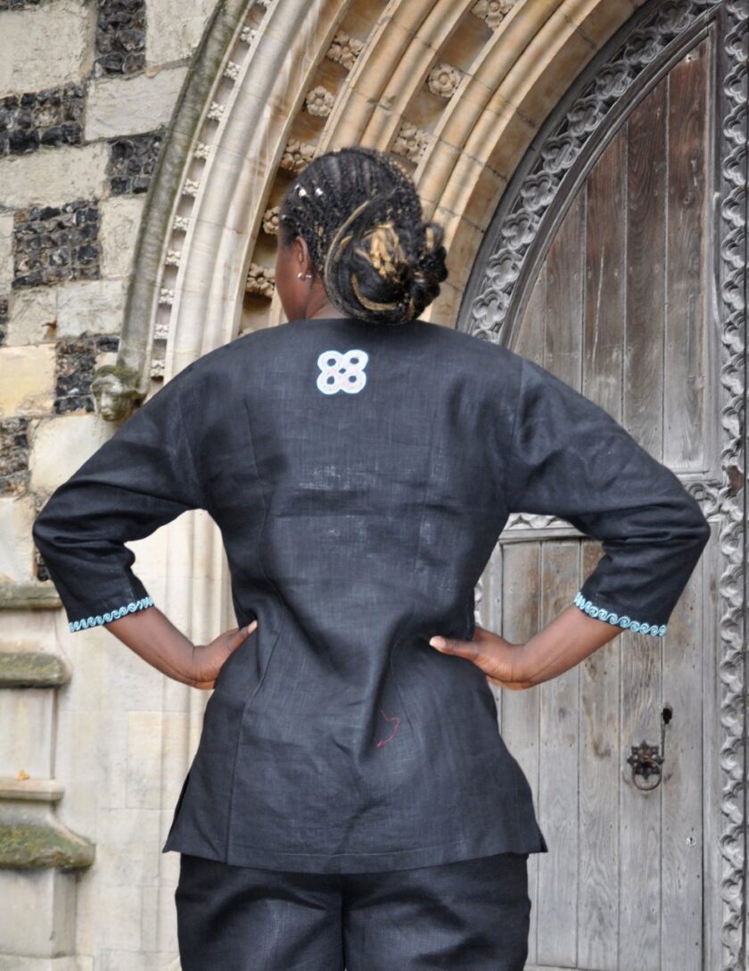Close back shot of our ladies black traditional African linen trouser suit / pantsuit with cream, turquoise and orange embroidery on the back.