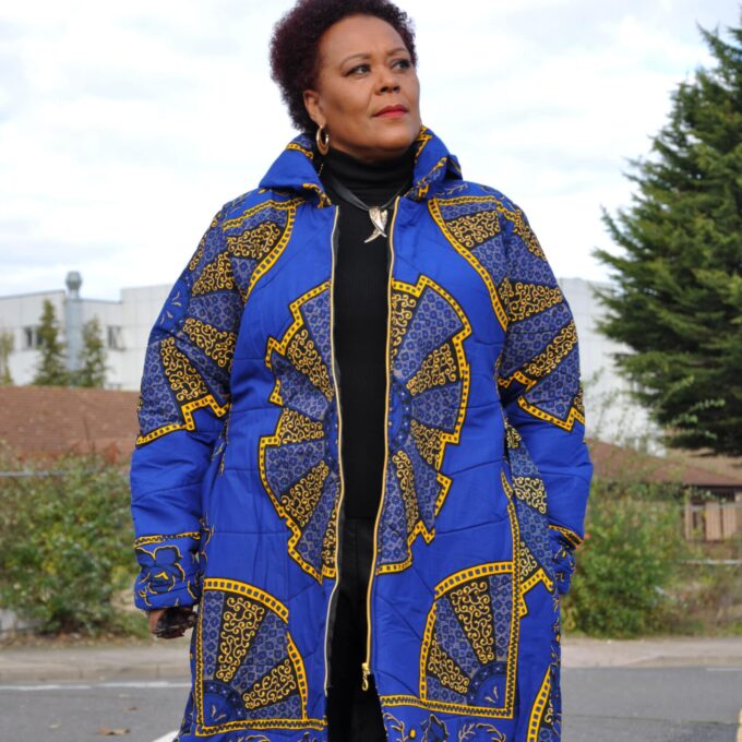 Frontal of model wearing a ladies African puffer coat in blue and gold Akufo Ankara all over print.