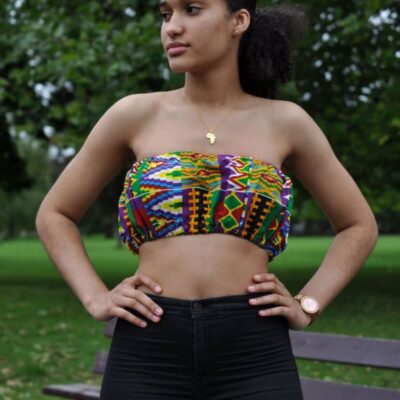 Frontal of model wearing a colourful African print crop top in all over Kente pattern.