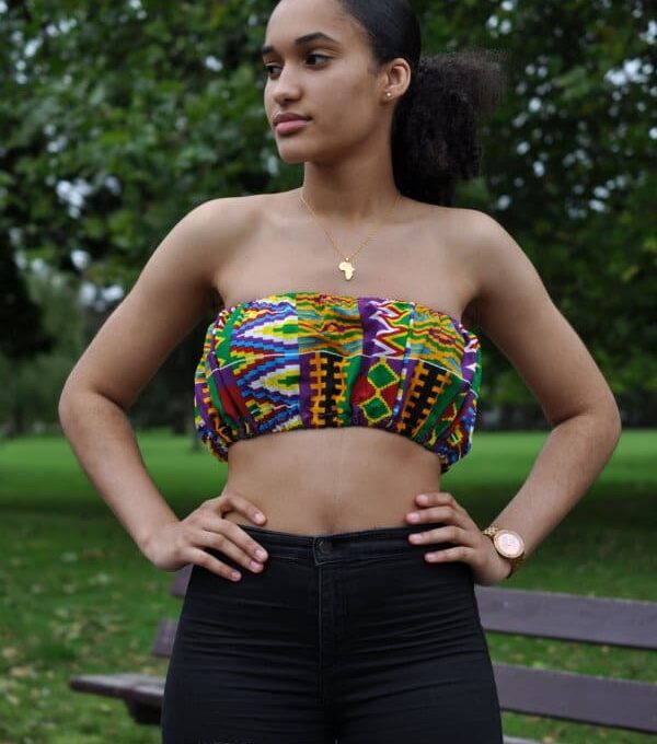 Frontal of model wearing a colourful African print crop top in all over Kente pattern.