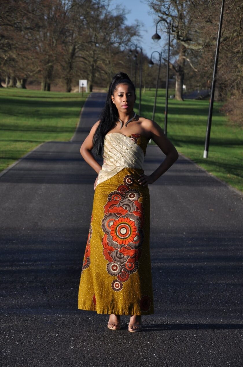Full frontal of model wearing a long strapless cream lace and mustard yellow Ankara fit and flare dress with African print rosette detail on the skirt.