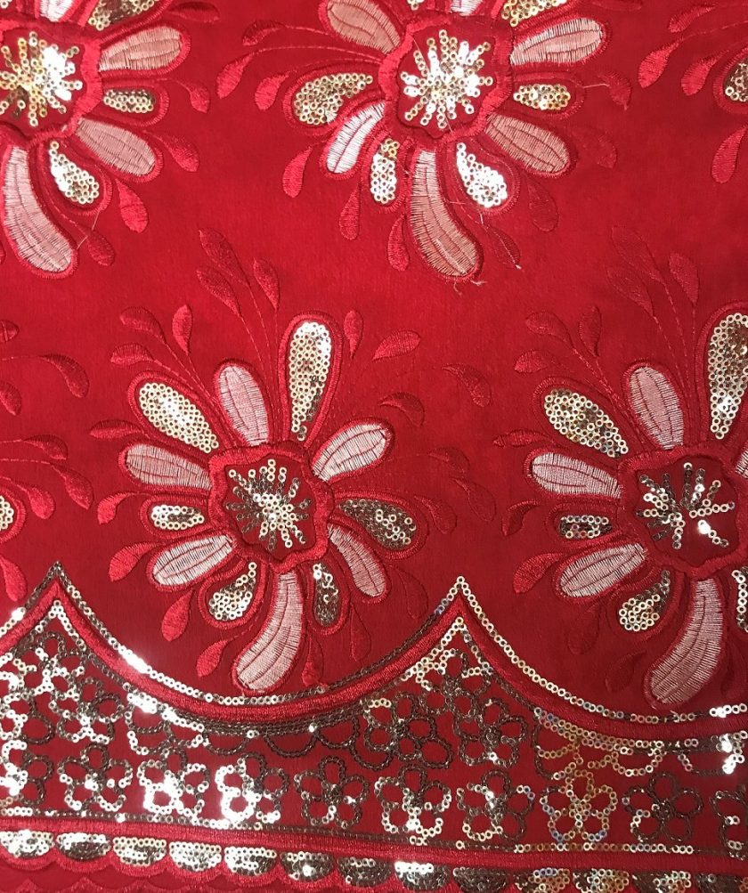 Close up of red Nigerian Geroge lace with gold embellishment.