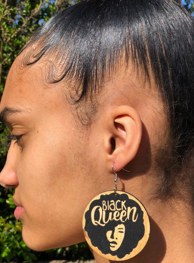 Shot of round black painted wooden African dangle earrings with Black Queen gold wording.