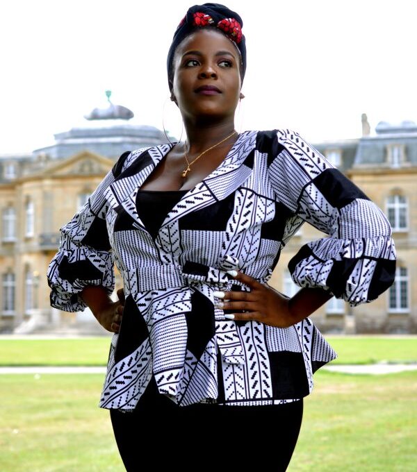 Frontal of model wearing a ladies white and black peplum top in all over graphic African print.