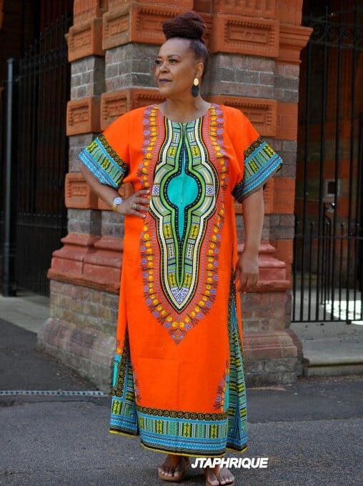 Full frontal of model wearing this dress in bright orange & multi-coloured print.