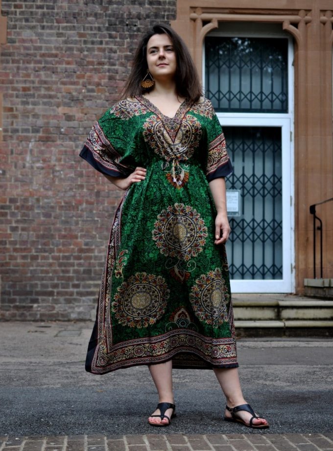 Full frontal of model wearing a dark green lightweight kaftan dress which is perfect for holiday or travel.
