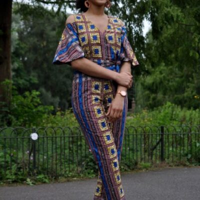 Frontal of model wearing a blue and gold African Ankara print jumpsuit with cold shoulder and butterfly sleeves.