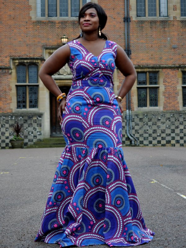 Frontal of model wearing a sleeveless blue and purple fit and flare special occasion silhouette dress in all over African Ankara print pattern.