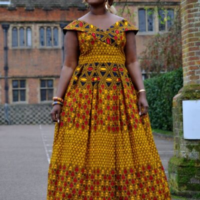 Full Frontal of model wearing a cap sleeve long a-line dress with full flounce skirt. Features all over vibrant African print.