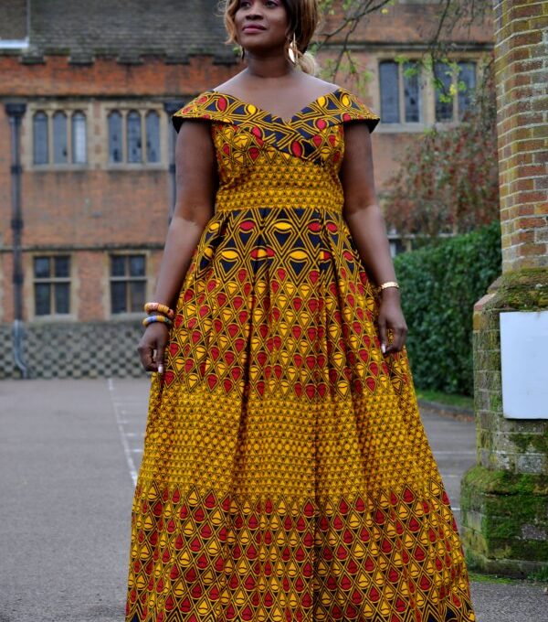 Full Frontal of model wearing a cap sleeve long a-line dress with full flounce skirt. Features all over vibrant African print.
