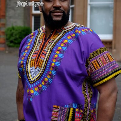 Close shot of model wearing a men's purple traditional African shirt with Angelina dashiki pattern.
