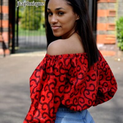 Close back image of model wearing a red balloon sleeve crop top in all over swirly African Ankara print.