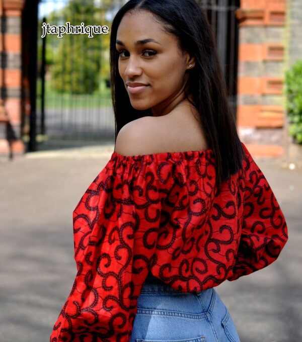 Close back image of model wearing a red balloon sleeve crop top in all over swirly African Ankara print.