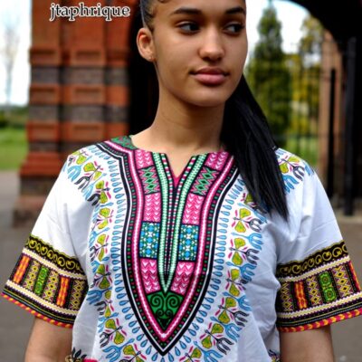 Close front shot of model wearing a ladies white traditional African Dashiki shirt with pink and multi-coloured Angelina pattern on chest, sleeves and hem.