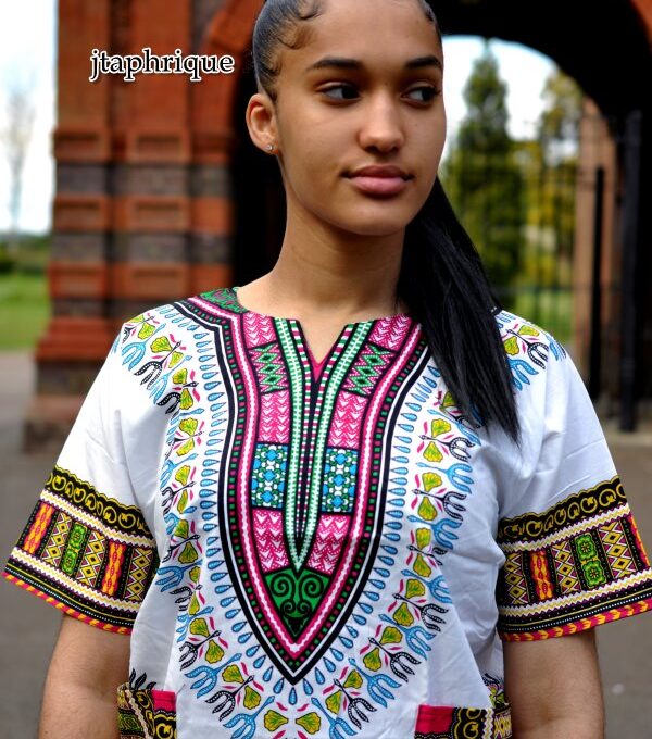 Close front shot of model wearing a ladies white traditional African Dashiki shirt with pink and multi-coloured Angelina pattern on chest, sleeves and hem.
