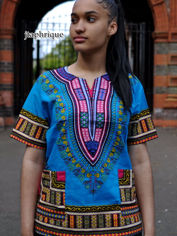 Close front shot of model wearing a ladies light blue and traditional African Dashiki shirt with pink and multi-coloured Angelina pattern on chest, sleeves and hem.