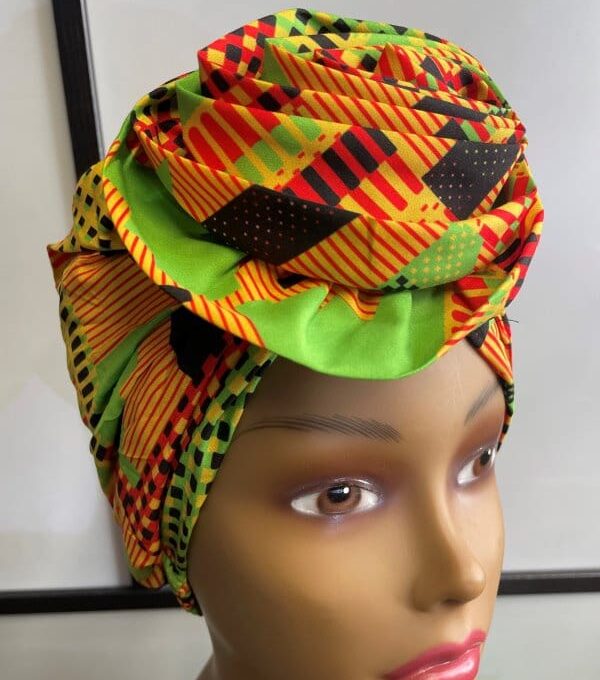 Close shot of mannequin wearing a pre-tied head wrap or turban in all over orange and multi-coloured African print.