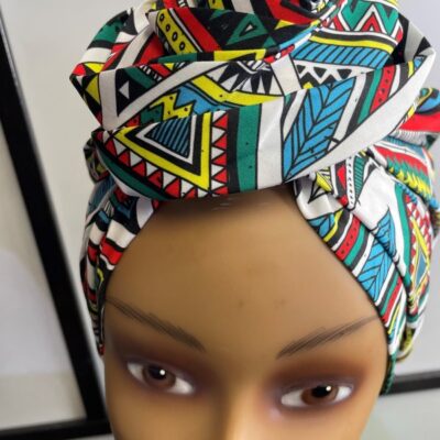 Close shot of mannequin wearing a pre-tied head wrap or turban in all over blue and multi-coloured African print.