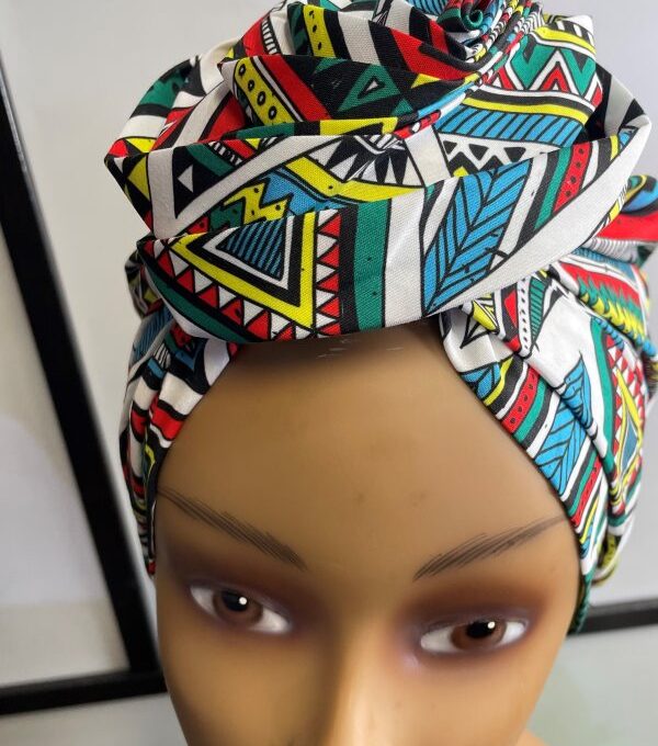 Close shot of mannequin wearing a pre-tied head wrap or turban in all over blue and multi-coloured African print.