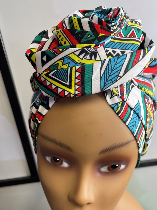 Close shot of mannequin wearing a pre-tied head wrap or turban in all over blue and multi-coloured African print.