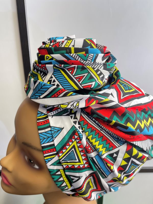 Side shot of mannequin wearing a pre-tied head wrap or turban in all over blue and multi-coloured African print.