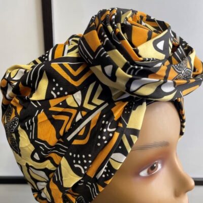 Close shot of mannequin wearing a pre-tied head wrap or turban in all over yellow and multi-coloured African print.