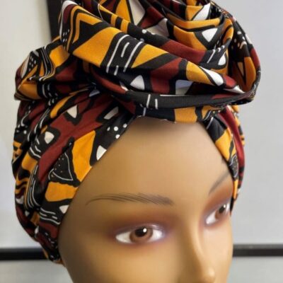 Close shot of mannequin wearing a pre-tied head wrap or turban in all over yellow, brown, white and black geometric African print.