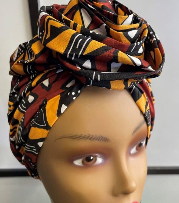 Close shot of mannequin wearing a pre-tied head wrap or turban in all over yellow, brown, white and black geometric African print.