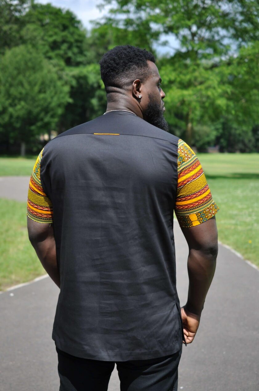 Back shot of model showing this African-inspired shirt with solid black back and dashiki print on the sleeves.