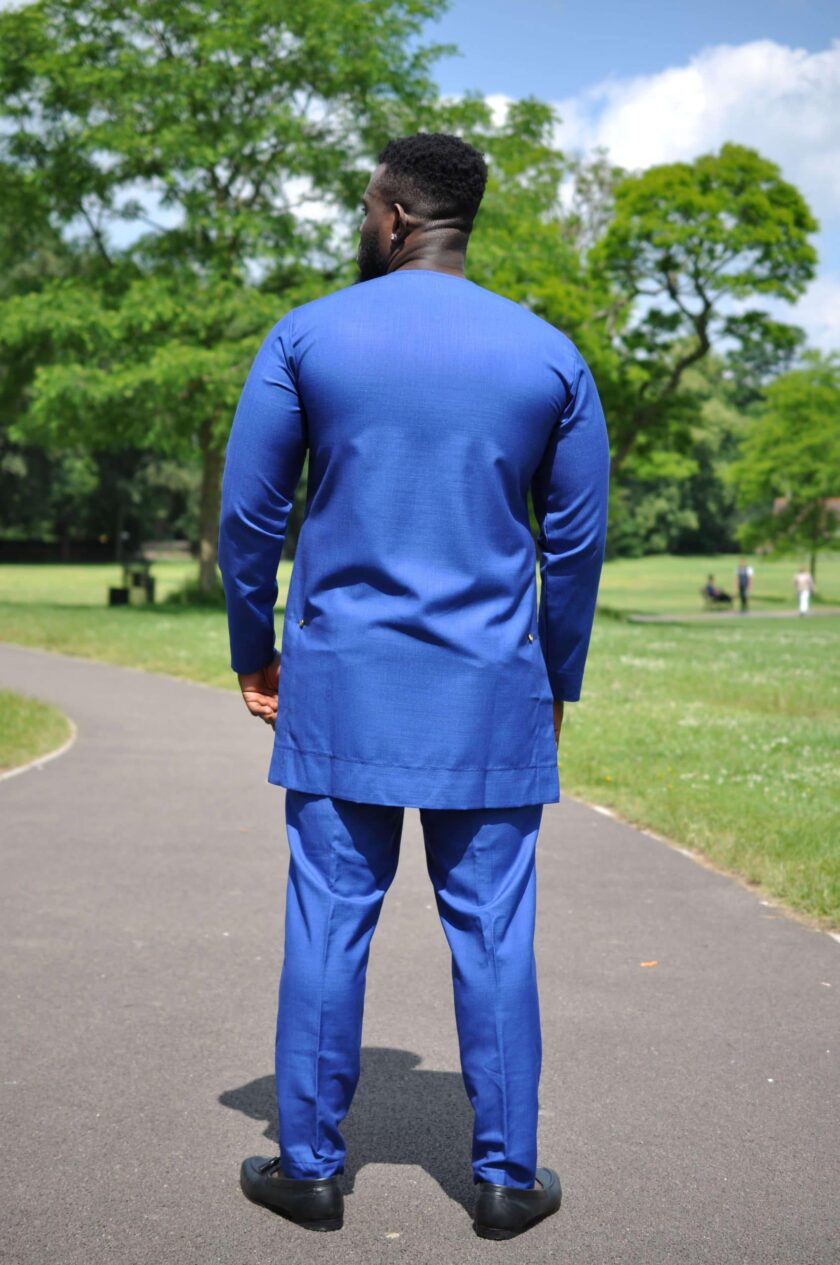 Back shot of model wearing a solid blue African men's suit made from suiting fabric. Can order suit in plus size.
