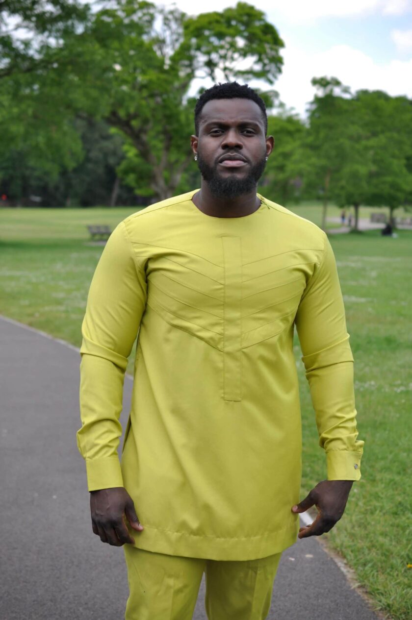 Close frontal of model wearing a chartreuse yellow men's African suit top with embroidery in matching colour.
